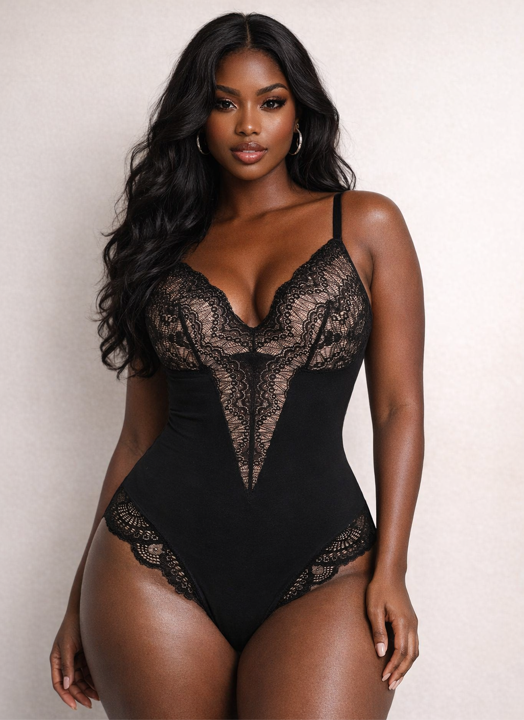 Woman wearing a black lace bodysuit against a plain background