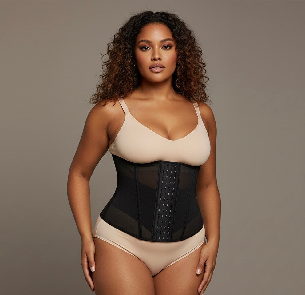 Woman wearing a beige bra and black waist trainer against a neutral background
